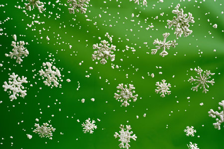 snowflakes in motion on a green background close-upの素材