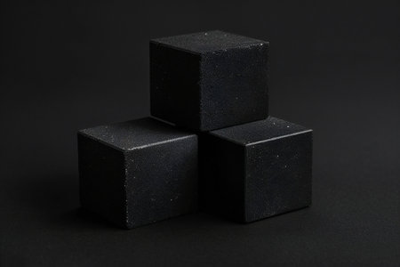 Three black cubes on a black background. Shallow depth of field.の素材