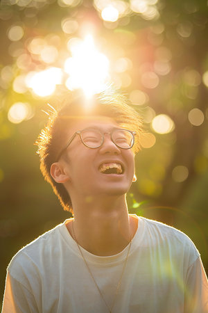 Portrait of a happy young Asian man with glasses in the parkの素材