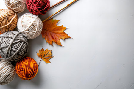 Woolen yarn balls, knitting needles and autumn leaves on white background
