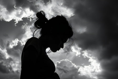 Silhouette of a pregnant woman against the sky with clouds.の写真素材