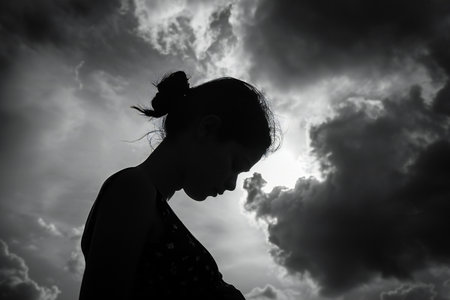 Silhouette of a woman against the sky with dramatic clouds.の写真素材