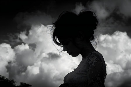 Silhouette of a beautiful woman in white dress against cloudy skyの写真素材