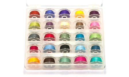 Box of colorful bobbins on white background