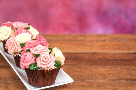 Roses cupcake on wooden floor with multicolor backgroundの写真素材