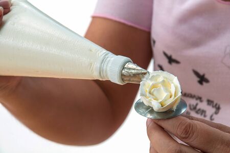 Woman is making rose from cream for cake decorationの写真素材