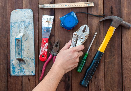 Construction hand tools with hand over wooden floorの写真素材