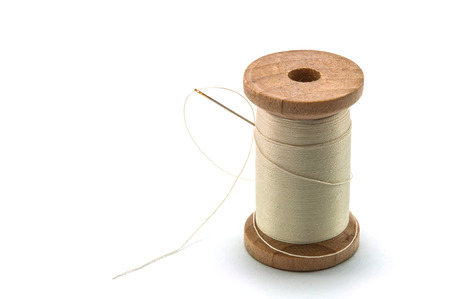 Isolated wooden spool of cream thread with a needleの写真素材