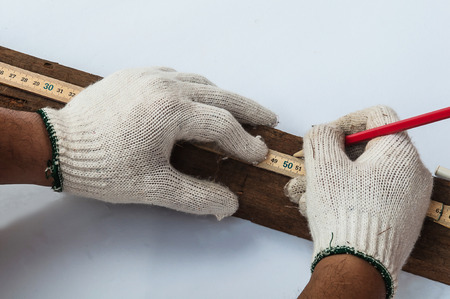 Carpenter's hands using wooden folding ruler to measure his wood cutting work