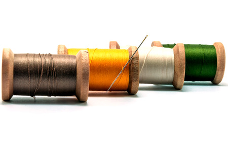 Isolated wooden spools of thread with a needle