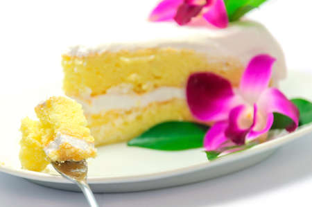 Coconut cake decorated by purple orchid and green leaf on white plate