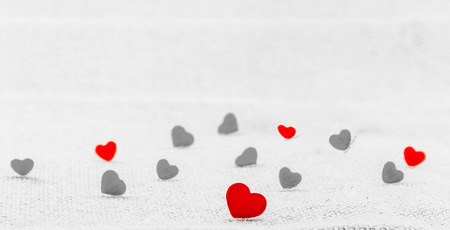 Hearts in color and gray tone putting on sack fabric. Photo is focused at the front heart.の写真素材