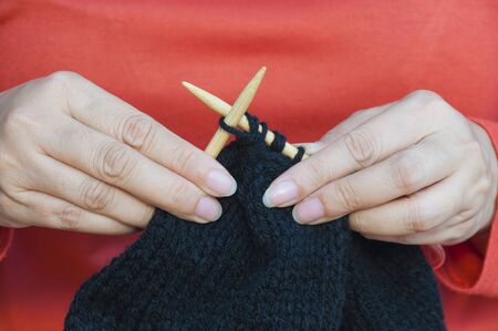 Woman's hands is making black hat knittingの写真素材