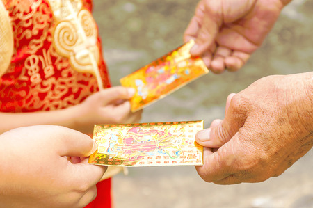 Grandparent is giving money gift envelopes to his grandsons during Chinese new year festivalの写真素材