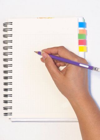 Lady's hand holding pencil ready to write an empty notebook with sticky note memoの写真素材