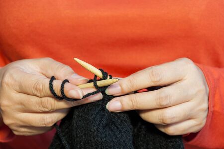 Woman's hands is making black hat knitting