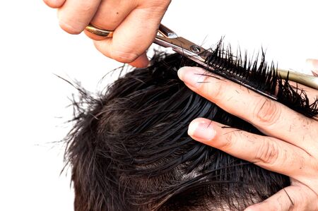 Hair dresser is cutting a boy hair over white background, focus at scissor