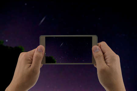 Man is using mobile phone take photo of Geminid meteorの写真素材