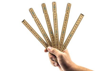 Man's hand holding wood folding measuring stick, hand tool, isolated over white.