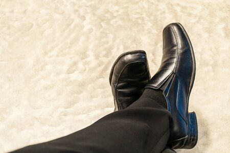 Top view of old black pants and leather shoes of relax sitting businessman on cement floor. Photo is focused at shoes.の写真素材