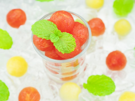 Small sphere shape of cantaloupe and watermelon in a glass with mint and ice decorationの写真素材
