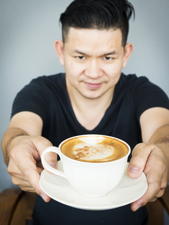 A barista man is serving coffee cup to youの写真素材
