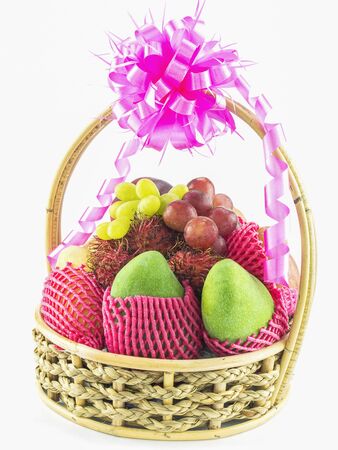 Fruit basket gift with pink ribbon bow isolated over whiteの写真素材