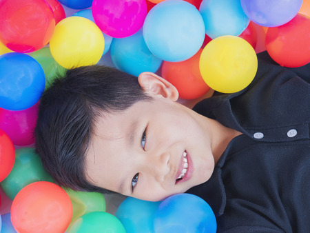 Happy Asian kid with colorful toy ballsの写真素材