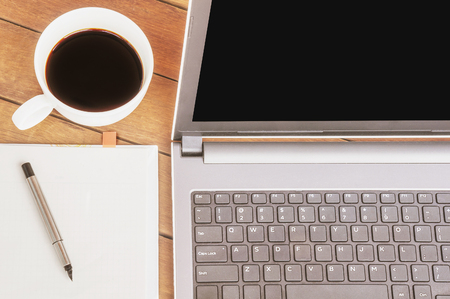 Vintage style photo of business work concept with computer laptop coffee white note paper and pen on wooden tableの写真素材