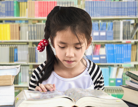 Asian girl is reading book in a library