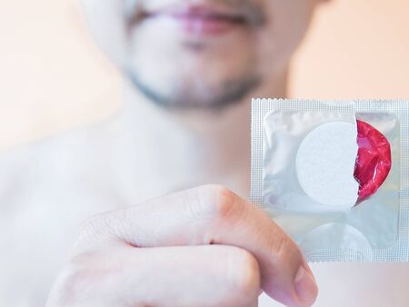 Man is showing red condom safe sex conceptの写真素材