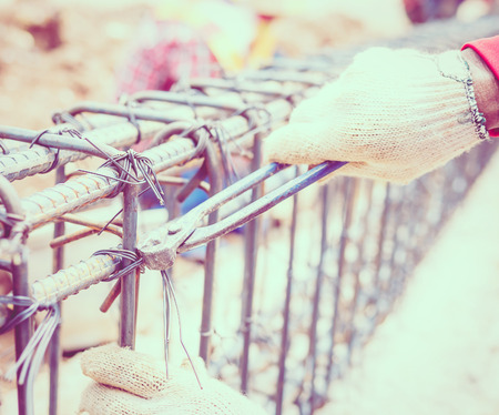 Vintage style photo of construction workers are installing steel rods in reinforced concrete beamの写真素材