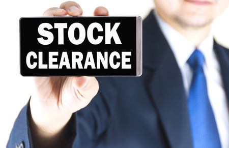 STOCK CLEARANCE word on mobile phone screen in blurred young businessman hand over white background, business conceptの写真素材