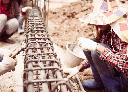 Vintage style photo of construction workers are installing steel rods in reinforced concrete beamの写真素材