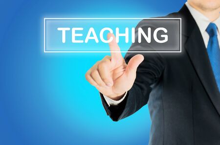 Business man is pushing TEACHING transparent button word over blue gradient background, business conceptの写真素材
