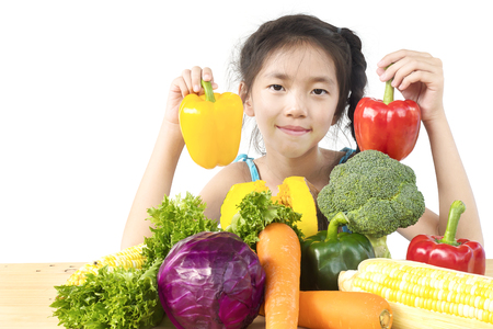 Asian lovely girl showing enjoy expression with fresh colorful vegetables isolated over white backgroundの写真素材