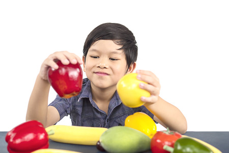 Asian healthy boy showing happy expression with variety colorful fruit and vegetable over white backgroundの写真素材