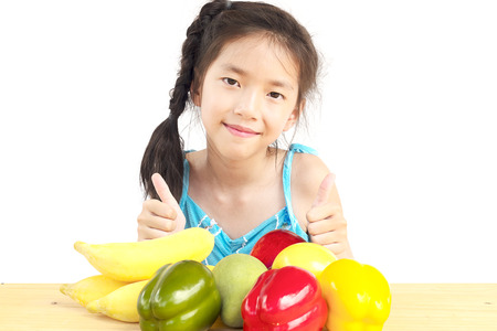 Asian healthy gril showing happy expression with variety colorful fruit and vegetable over white backgroundの写真素材