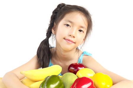 Asian healthy gril showing happy expression with variety colorful fruit and vegetable over white backgroundの写真素材