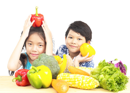 Asian boy and girl showing enjoy expression with fresh colorful vegetables isolated over white backgroundの写真素材