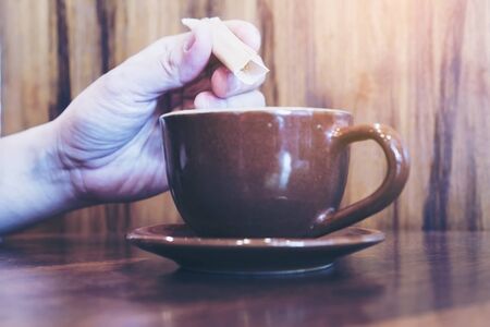 Selective focus of man putting sugar into coffee cupの写真素材