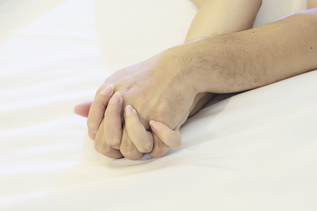 Man holding woman hand on white bed, couple sexual conceptの写真素材