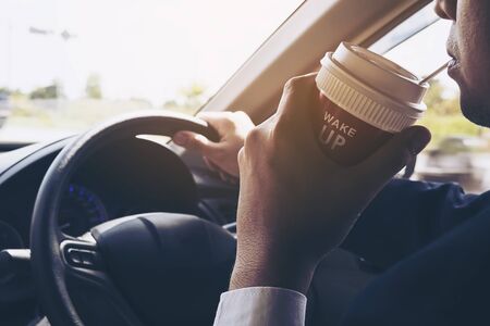 Man driving car while holding a cup of coffeeの写真素材