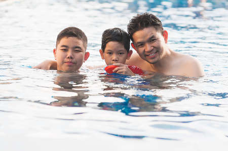 Happy dad and son swimming in a poolの写真素材