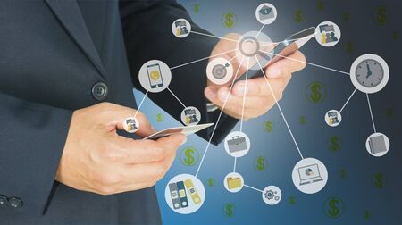 Businessman is using mobile phone and holding credit card with office money icons overlay - online...