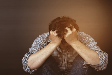 Sad man holding head with handの写真素材