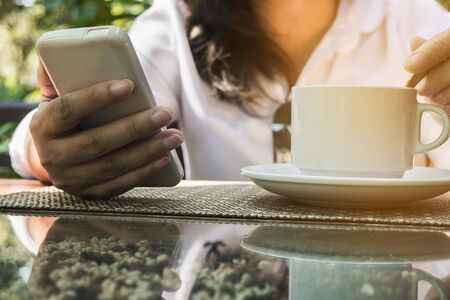 Lady using mobile white drinking coffeeの写真素材