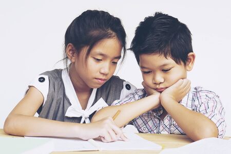 Sister try to teach her naughty younger brother to do homework  isolated over white backgroundの写真素材