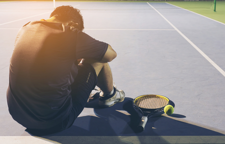 Sad tennis player sitting in the court after lose a matchの写真素材