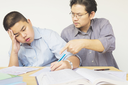 Asian father teaching homework to his 14 years son seriouslyの写真素材
